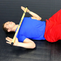 Man lying down with a tan 1 lb CanDo WaTE exercise bar